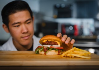 A burger with vegan patty and fries on a cutting board